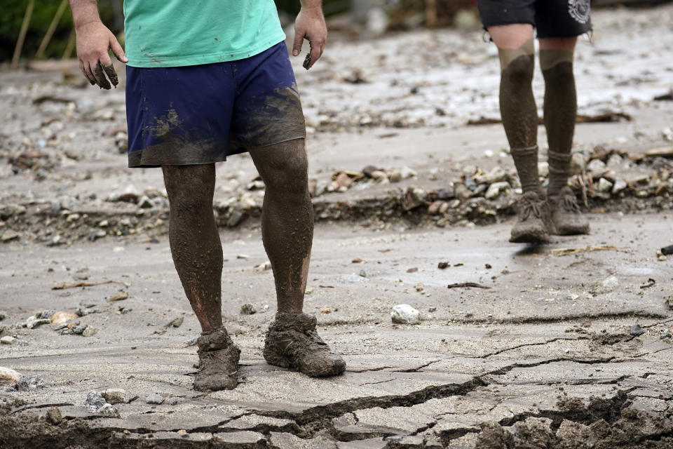 Residents Brooke Horspool, left, and his son Andrew Horspool show mud up to their knees while helping a neighbor in the aftermath of Tropical Storm Hilary Monday, Aug. 21, 2023, in Yucaipa, Calif. Scientists figure a natural El Nino, human-caused climate change, a stubborn heat dome over the nation’s midsection and other factors cooked up Hilary’s record-breaking slosh into California and Nevada.(AP Photo/Marcio Jose Sanchez)