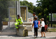 A man speaks to a worker sitting next to a security fence surrounding the U.S. ambassador's residence, ahead of the U.S. presidential visit, in Regents Park, London, Britain July 11, 2018. REUTERS/Henry Nicholls