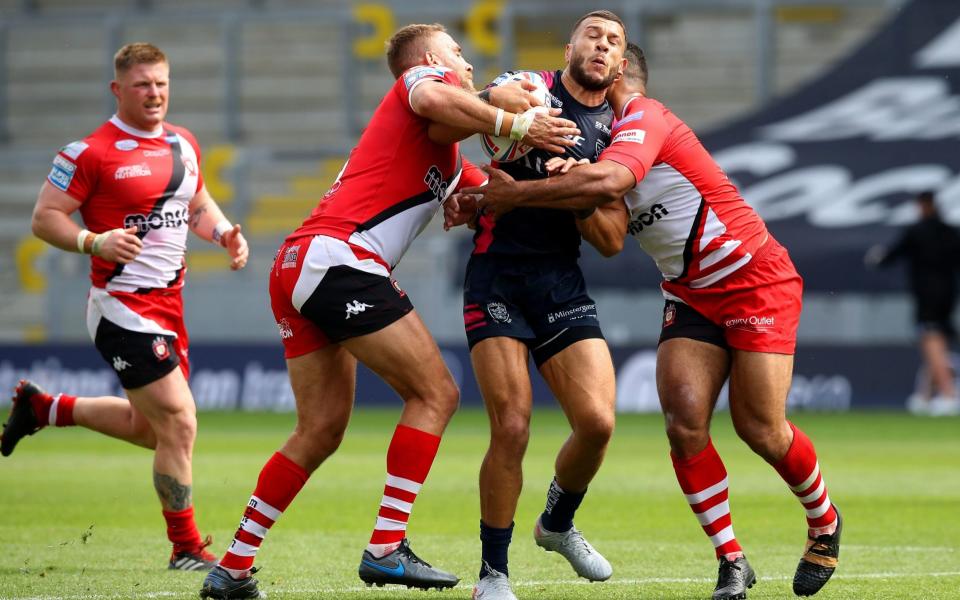 Hull FC's Carlos Tuimavave (centre) being tackled by Salford Red Devils' Sebastine Ikahihifo (right) and Lee Mossop. - PA