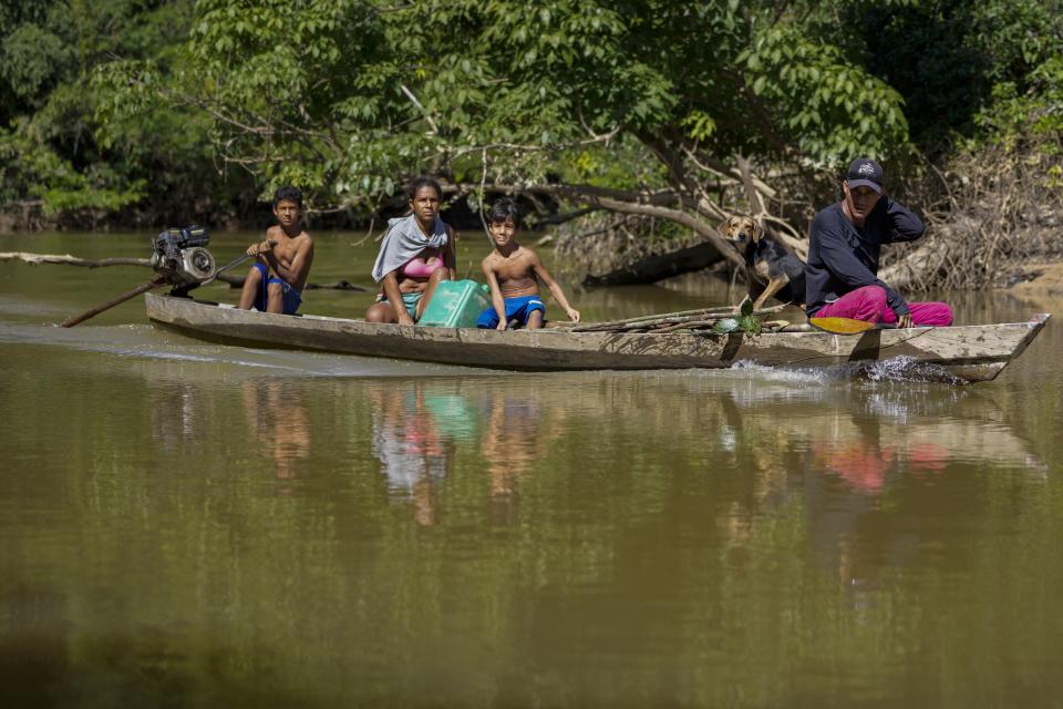 A family of settlers ride a boat on Branco River in an extractive reserve in Jaci-Parana, Rondonia state, Brazil, Tuesday, July 11, 2023. Meat processing giant JBS SA and three other slaughterhouses are facing lawsuits seeking millions of dollars in environmental damages for allegedly purchasing cattle raised illegally in the area. (AP Photo/Andre Penner)