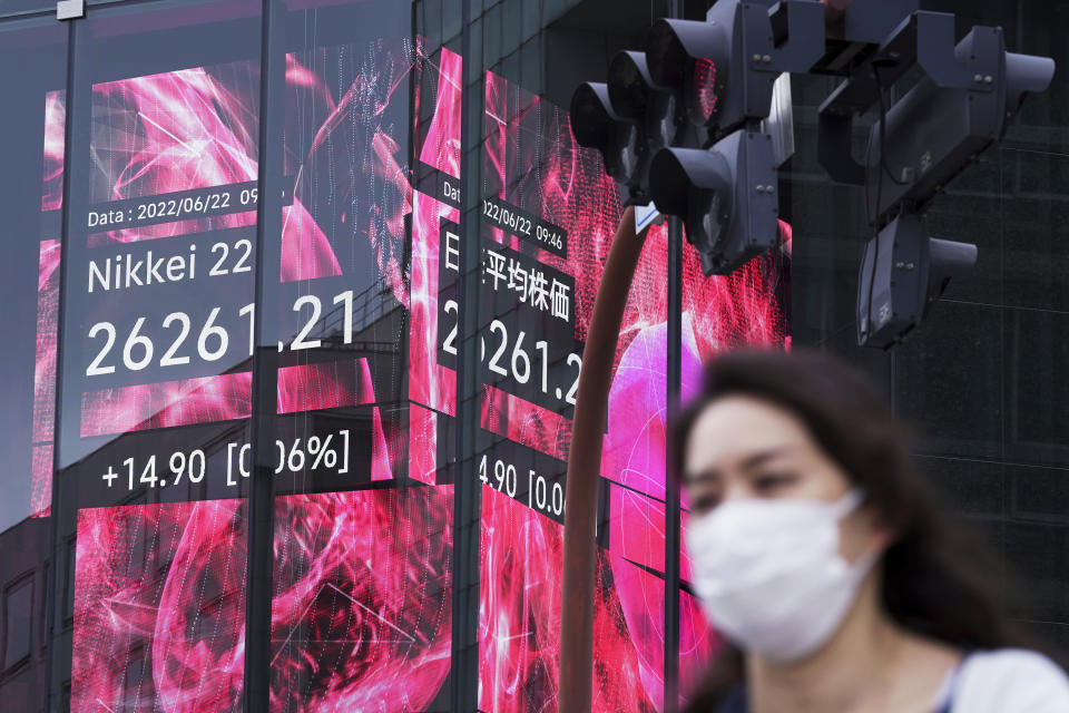 A woman wearing a protective mask rides a bicycle in front of an electronic stock board showing Japan's Nikkei 225 index at a securities firm Wednesday, June 22, 2022, in Tokyo. Asian shares were mostly lower Wednesday as markets shrugged off a Wall Street rally and awaited congressional testimony by Federal Reserve Chair Jerome Powell. (AP Photo/Eugene Hoshiko)