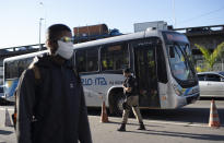 A municipal police officer walks past a bus at a checkpoint to check documents and take body temperatures, amid increased restrictions on movements in an effort to curb the spread of the new coronavirus in Niteroi, Brazil, Monday, May 11, 2020. (AP Photo/Silvia Izquierdo)