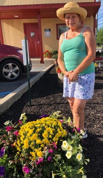 Dianne Poplawski, also known as the Flower Lady, stands behind one of the barrels of flowers that she tends in the parking lot south of Bobby’s Restaurant.