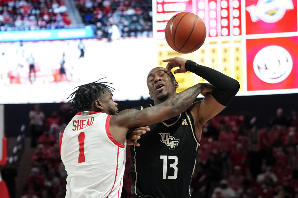 Houston's Jamal Shead (1) and Central Florida's C.J. Kelly (13) reach for a loose ball during the first half of an NCAA college basketball game Saturday, Dec. 31, 2022, in Houston. (AP Photo/David J. Phillip)