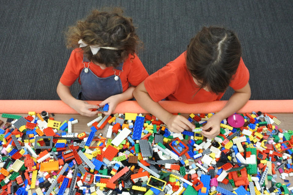 Above view of two girls playing with building bricks child benefit