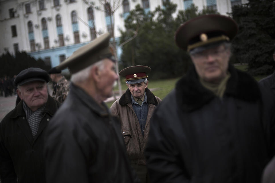 FILE - In this Saturday, March 8, 2014 file photo, an elderly Ukrainian man stands at Lenin Square with colleagues, all of them dressed in army uniforms from the U.S.S.R., during a pro Russia rally in Simferopol, Ukraine. Despite the pebble beaches and cliff-hung castles that made Crimea famous as a Soviet resort hub, the Black Sea peninsula has long been a corruption-riddled backwater in economic terms. The Kremlin, which decided to take the region from Ukraine after its residents voted in a referendum to join Russia, has begun calculating exactly what it will cost to support Crimea’s shambolic economy _ which one Russian minister described as “no better than Palestine.” (AP Photo/Manu Brabo, File)