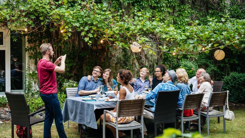 man taking photo of family having lunch outdoors