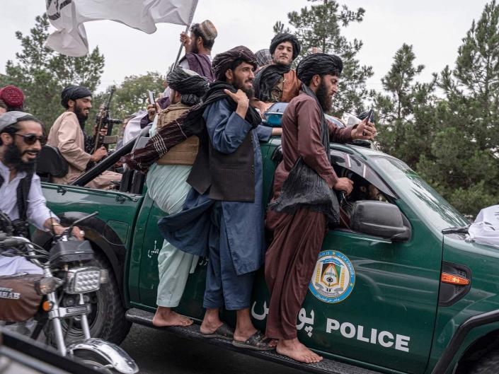 Taliban fighters holding onto a truck