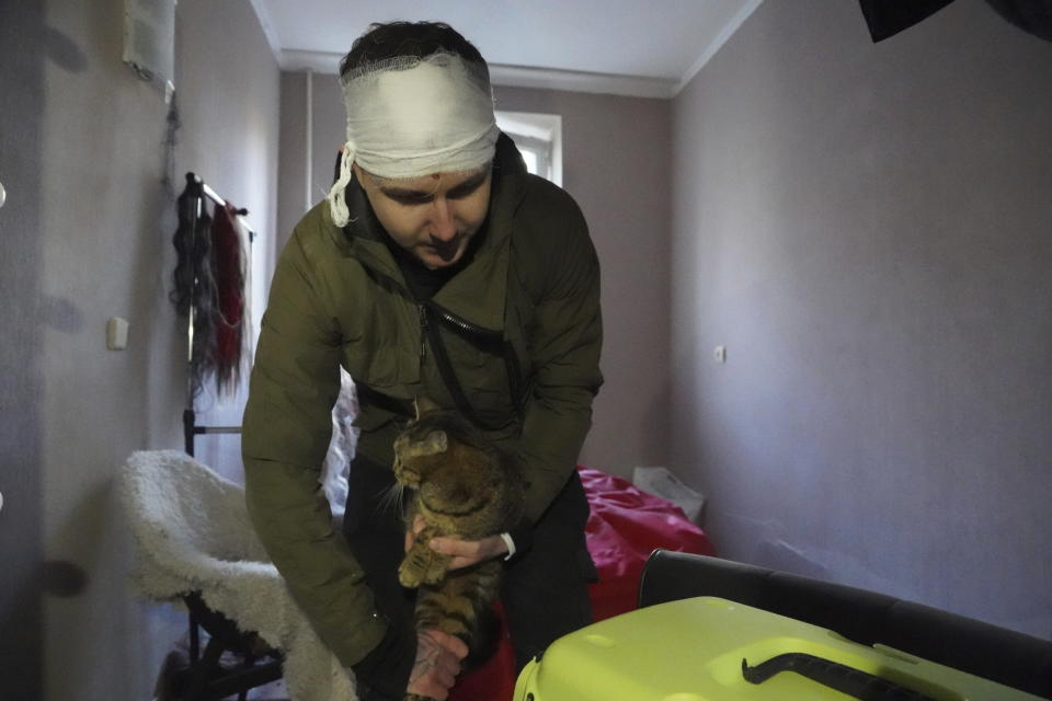 An injured man evacuates his cat from a building hit by a Russian strike in Kharkiv, Ukraine, Wednesday, March 27, 2024. (AP Photo/Andrii Marienko)