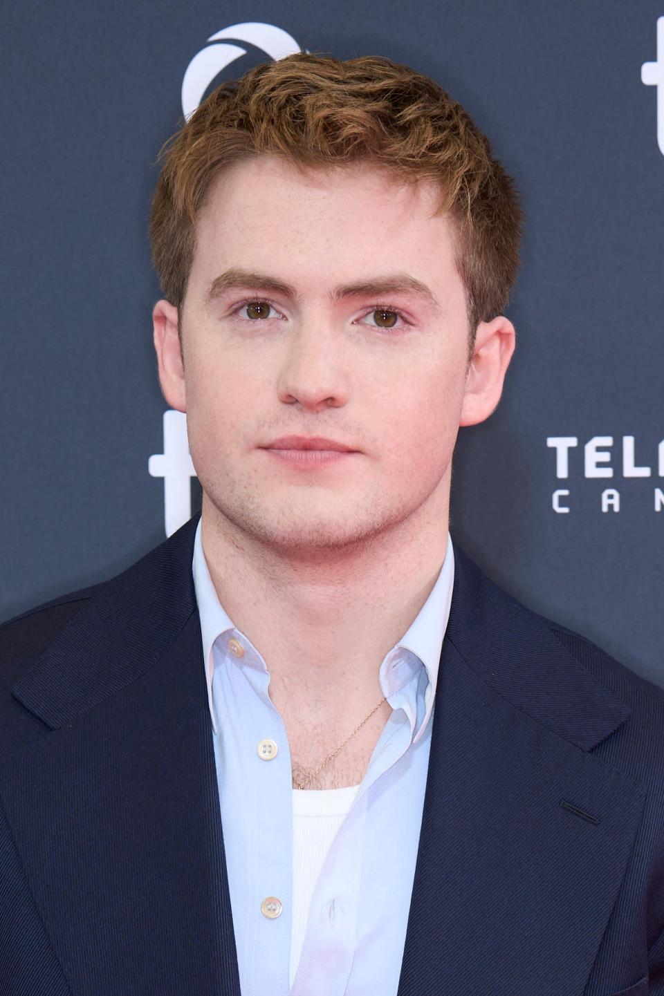 Kit Connor on a red carpet wearing a dark suit and light blue shirt