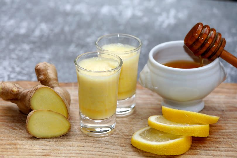 Drink with ginger root, honey and lemon on wooden background.