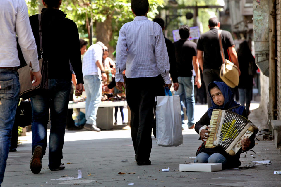 In this Thursday, May 23, 2013, Reyhaneh, plays music, hoping to earn money from passers-by, in Tehran, Iran. On the roughneck streets in south Tehran, paramilitary volunteers look to the most hard-line presidential candidate as the best defender of the Islamic system. On the other end of Tehran's social ladder, a university professor plans to snub next week's election. In between is a mix of splintered views, apathy and indecision based on dozens of AP interviews suggesting a still wide open race. (AP Photo/Vahid Salemi)