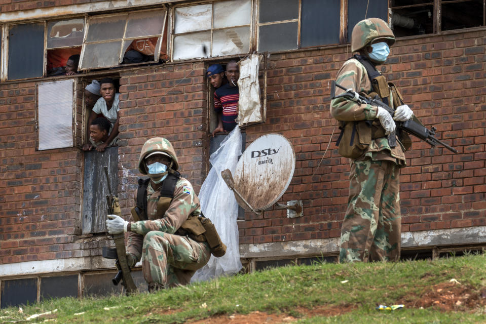 Fuerzas de la Defensa Nacional Sudafricana patrullan un hostal de hombres en el municipio de Alexandra, al oriente de Johannesburgo, el sábado 28 de marzo. (AP Foto/Jerome Delay)