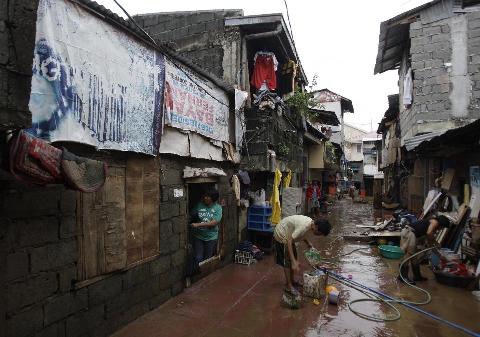 Luzviminda Limas, left, checks her house after floods recede in suburban Marikina city, east of Manila, Philippines on Friday Aug. 10, 2012. The 54-year-old widow said the floods this week brought back memories of the 2009 deluge when she was huddled under an umbrella with one of her two daughters and her four-month old grandson on the roof of a day-care center beside her house as floodwaters rampaged through her neighborhood during a typhoon. The flood then destroyed her home. (AP Photo/Aaron Favila)