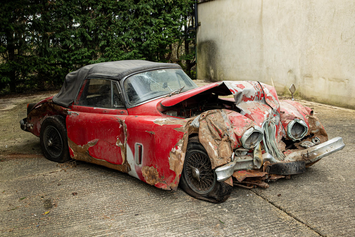 A red 1960 Jaguar XK150 S 3.8-Liter Drophead Coupe with a smashed front end