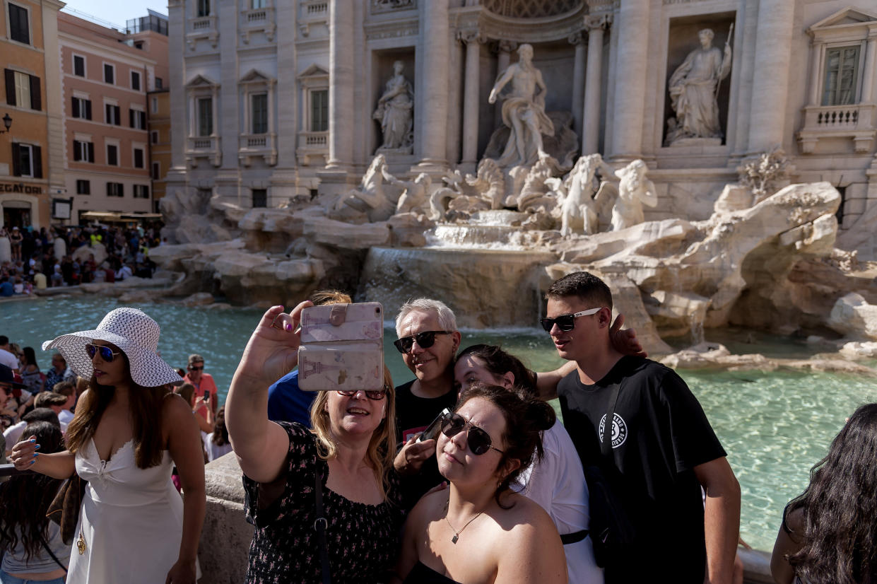 ROME, ITALY - AUGUST 29: Tourists take a selfie picture with a mobile phone in front of the Trevi Fountain on August 29, 2018 in Rome, Italy. Every day thousands of tourists visit the Trevi Fountain, which has become a real institution for tourists, who try their hand at the famous toss of a coin and take selfie and souvenir photos using this beautiful historical building as a backdrop.(Photo by Stefano Montesi - Corbis/Getty Images)