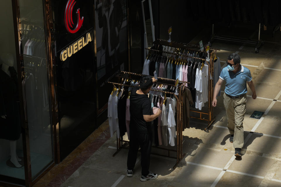 A man walks by as a vendor arranges clothes for sale outside his store at Ritan International Trade Center in Beijing on Wednesday, May 15, 2024. Data released on Friday, May 17 showed housing prices in China slumped for the first four months of the year, although factory output rose nearly 7%, as the country prepares to announce fresh measures to reinvigorate its ailing property industry. (AP Photo/Andy Wong)