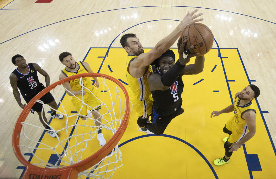 Los Angeles Clippers forward Montrezl Harrell (5) shoots under Golden State Warriors center Andrew Bogut during the second half of Game 2 of a first-round NBA basketball playoff series in Oakland, Calif., Monday, April 15, 2019. (Kyle Terada/Pool Photo via AP)