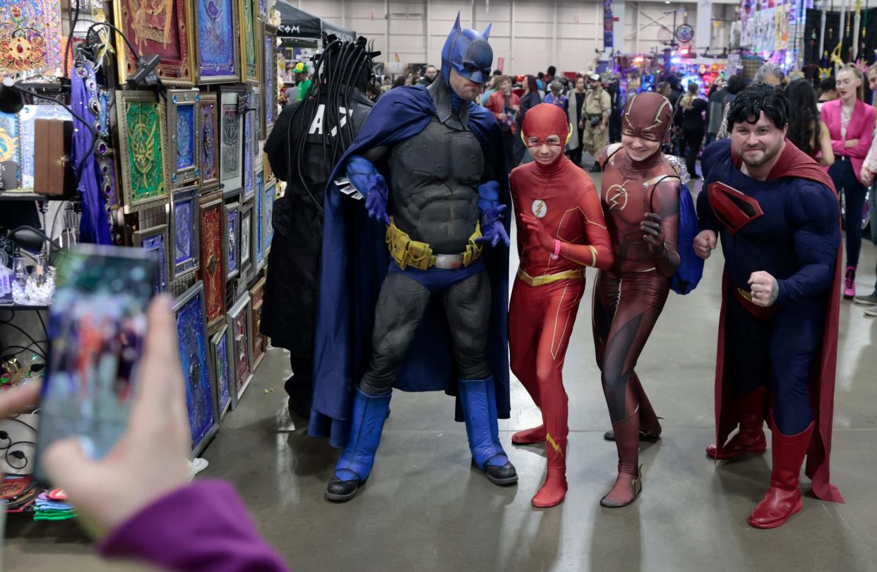 Brothers Ben Kaptur, left, and Mike Kaptur both who love The Flash pose for a photo on their iPhone with Batman and Superman cosplayers during the Motor City Comic Con at the Suburban Collection Showplace in Novi on Saturday, Nov. 11, 2023.
