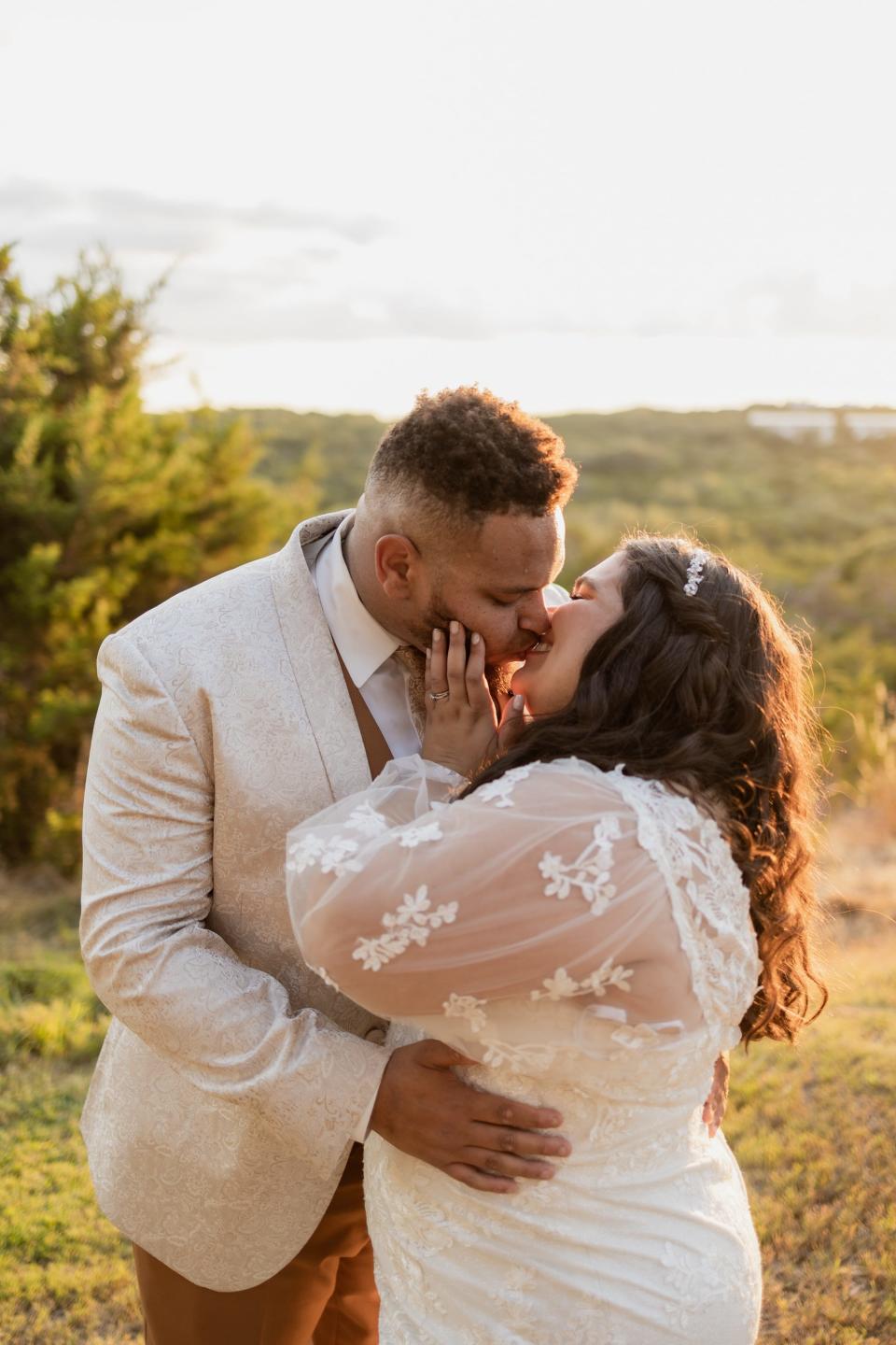 A bride and groom kiss in a field.