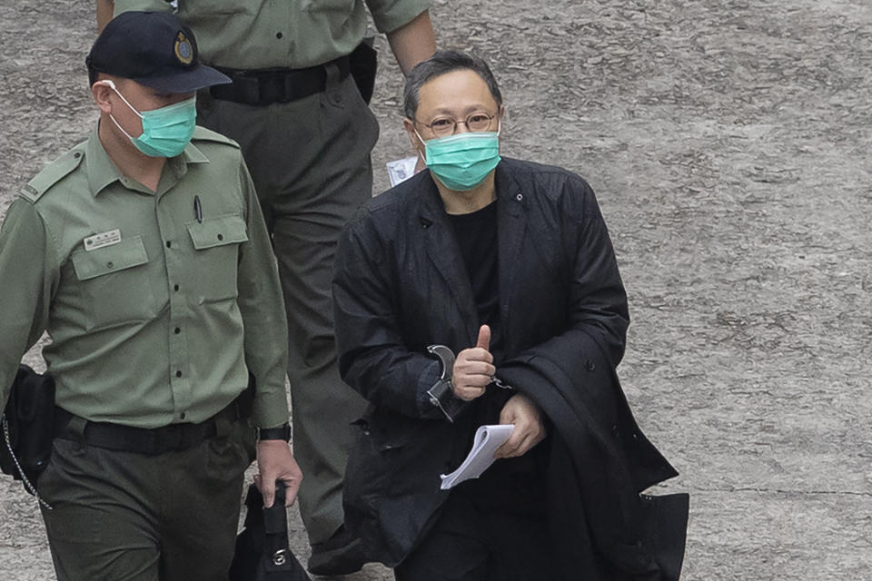 FILE - Former law professor Benny Tai, a key figure in Hong Kong's 2014 Occupy Central protests and also was one of the main organizers of the primaries, who was arrested under Hong Kong's national security law, gives the thumbs up as he is escorted by Correctional Services officers in Hong Kong March 2, 2021. A Hong Kong court began mitigation hearings for prominent pro-democracy activists who were convicted under a national security law and now face up to life in prison.(AP Photo/Kin Cheung, File)