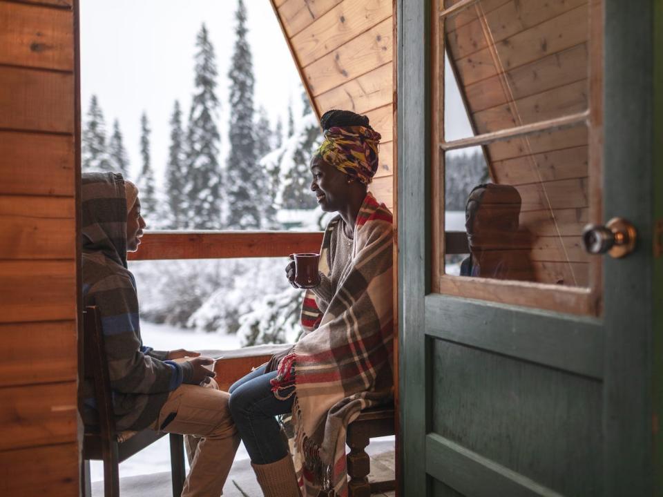 A mother and son sit on a balcony behind a winter wonderland.