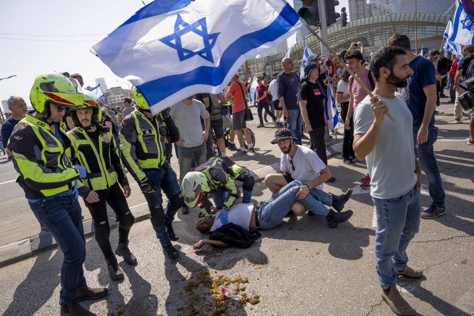 Medics treat an injured man after police on horseback were deployed and stun grenades used to disperse Israelis blocking a main road to protest against plans by Prime Minister Benjamin Netanyahu's new government to overhaul the judicial system, in Tel Aviv, Israel, Wednesday, March 1, 2023. (AP Photo/Oded Balilty)