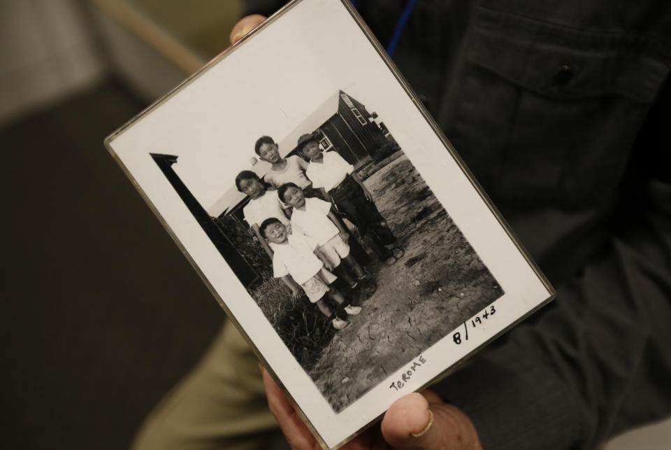 In this photo taken Tuesday, Feb. 11, 2020, Les Ouchida holds a 1943 photo of himself, front row, center, and his siblings taken at the internment camp his family was moved to, as he poses at the permanent exhibit titled "UpRooted Japanese Americans in World War II" at the California Museum in Sacramento, Calif. Ochida, who is a docent for the exhibit, and his family were forced to move in 1942 from their home near Sacramento to a camp in Jerome, Arkansas. Assemblyman Al Muratsuchi, D-Torrence has introduced a resolution to apologize for the state's role in carrying out the federal government's internment of Japanese-Americans. A similar resolution will be brought up before the state Senate by Sen. Richard Pan, D-Sacramento. (AP Photo/Rich Pedroncelli)