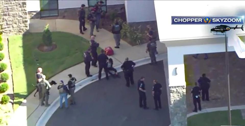 In this image from WSOC video, Charlotte-Mecklenburg police hold a person in custody outside a Hampton Inn & Suites hotel after a shooting at a nearby shopping center on Berewick Town Center Drive on Tuesday, October 4, 2022.