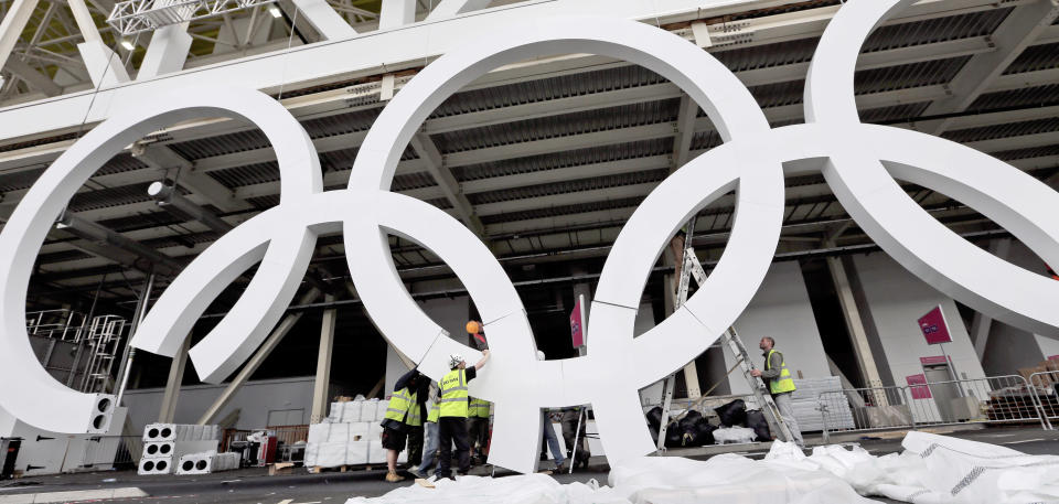 Workers assemble Olympic rings outside the Aquatics venue at the 2012 Summer Olympics in London, Saturday, July 14, 2012. (AP Photo/David J. Phillip)