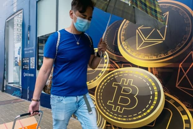 A pedestrian walks past signage for cryptocurrencies including ethereum bitcoin outside a cryptocurrency trader in the city. Beijing is cracking down on trading and mining of digital currencies. (Paul Yeung/Bloomberg - image credit)