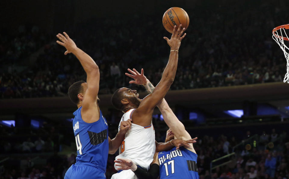 New York Knicks' Alec Burks (18) is fouled by Orlando Magic's Ignas Brazdeikis (17) as Magic's Jalen Suggs (4) trails the play during an NBA basketball game, Sunday, Oct. 24, 2021, in New York. (AP Photo/John Munson)