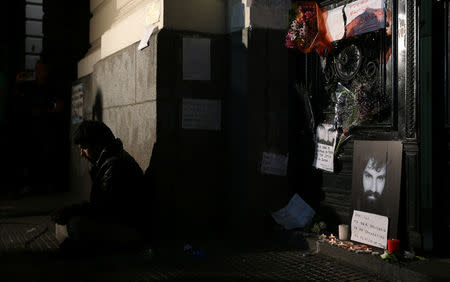 A man sits next to a portrait of Santiago Maldonado, a protester who went missing since security forces clashed with indigenous activists in Patagonia on August 1, 2017, at the entrance of a judicial morgue in Buenos Aires, Argentina October 20, 2017. REUTERS/Marcos Brindicci