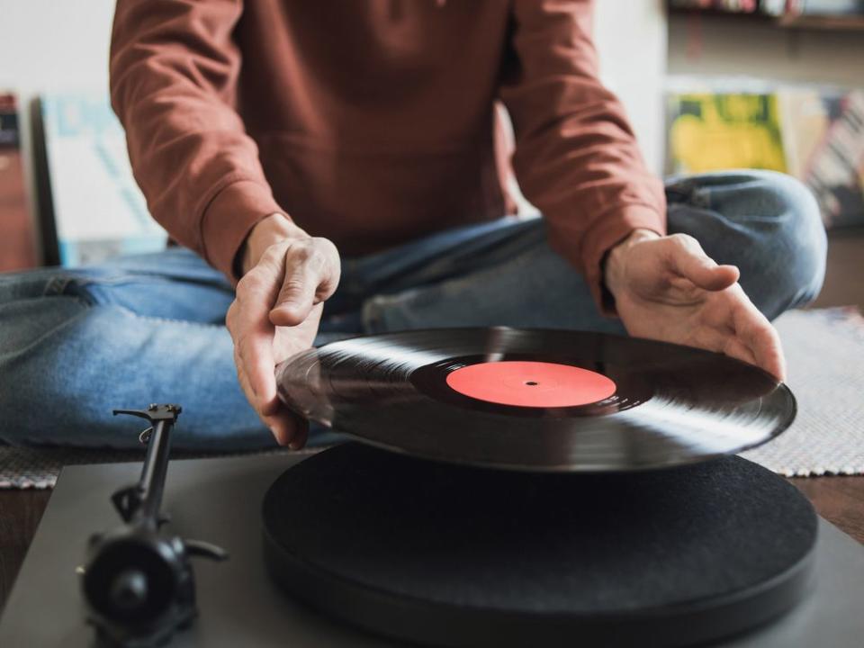 Man listening music, relaxing, enjoying life at home party. Turntable playing vinyl LP record