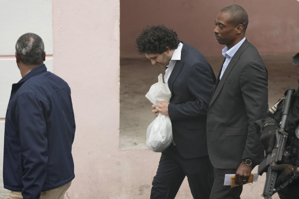 FTX founder Sam Bankman-Fried, center, is escorted from the Magistrate Court building in Nassau, Bahamas, Wednesday, Dec. 21, 2022, after agreeing to be extradited to the U.S. (AP Photo/Rebecca Blackwell)