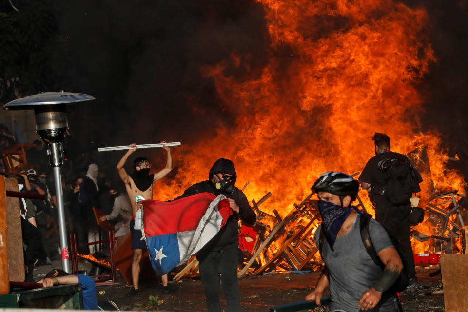 Demonstrators react as fire rages during an anti-government protest in Santiago, Chile on Oct. 28, 2019. (Photo: Henry Romero/Reuters)