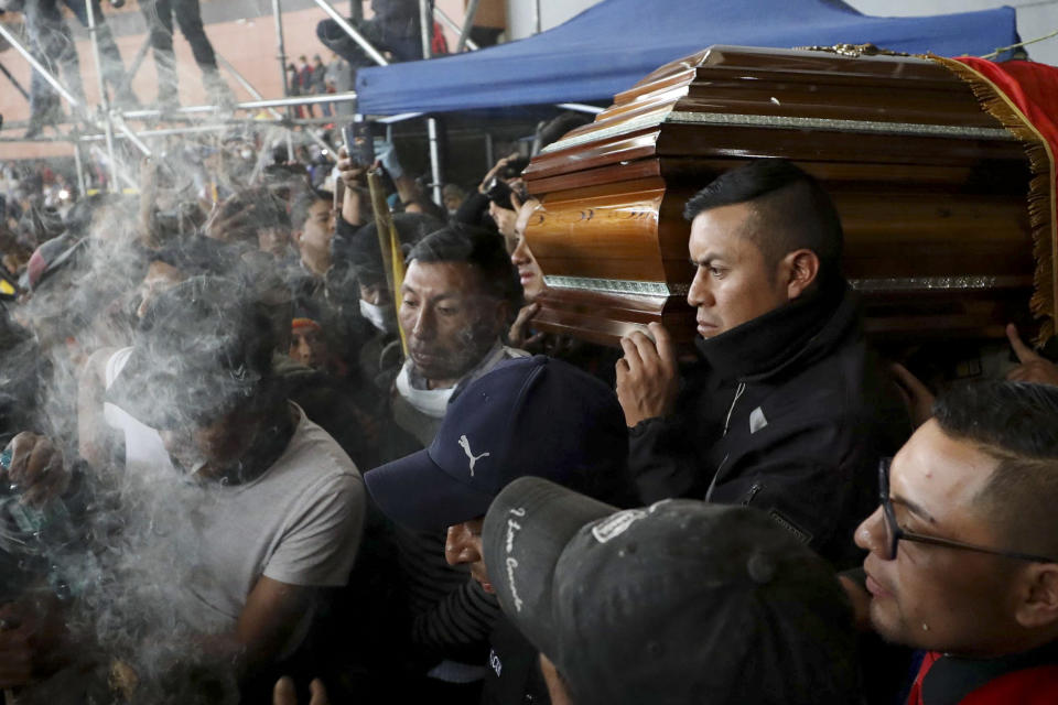 Police held captive by anti-government protesters, are forced to carry a coffin that contains the remains of a companion demonstrator who protesters say died during yesterday's national strike, in a procession inside the Casa de Cultura in Quito, Ecuador, Thursday, Oct. 10, 2019. An indigenous leader and four other people have died in unrest in Ecuador since last week, the public defender's office said Thursday. (AP Photo/Fernando Vergara)