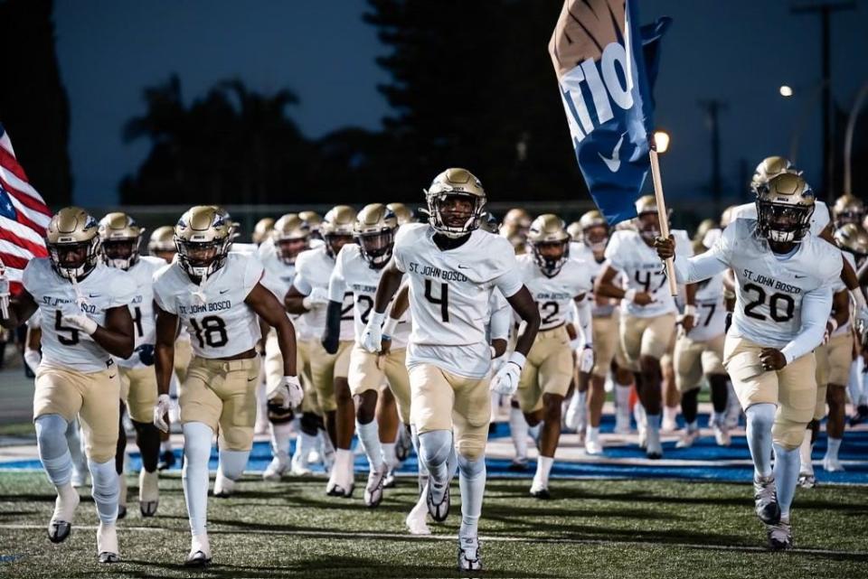 Louisville football signee Aaron Williams, middle, leads St. John Bosco High School onto the field before a game. A four-star cornerback prospect, Williams is a member of the Cardinals' much-anticipated 2023 recruiting class.