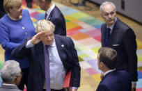 British Prime Minister Boris Johnson, center, salutes French President Emmanuel Macron, second right, during a round table meeting at an EU summit in Brussels, Thursday, Oct. 17, 2019. Britain and the European Union reached a new tentative Brexit deal on Thursday, hoping to finally escape the acrimony, divisions and frustration of their three-year divorce battle. (AP Photo/Olivier Matthys, Pool)