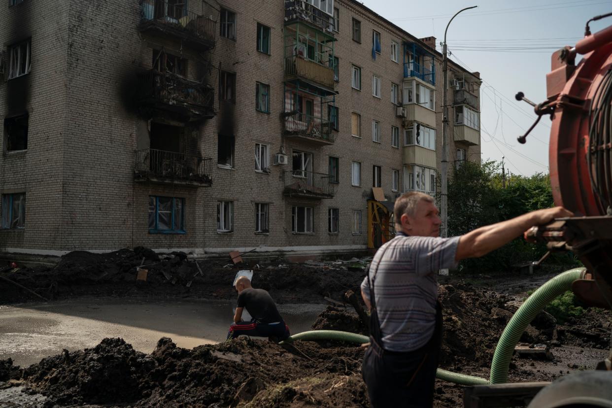 Workers drain water from a crater created by an explosion that damaged a residential building after a Russian attack in Slovyansk, Ukraine, Sunday, Aug. 28, 2022.