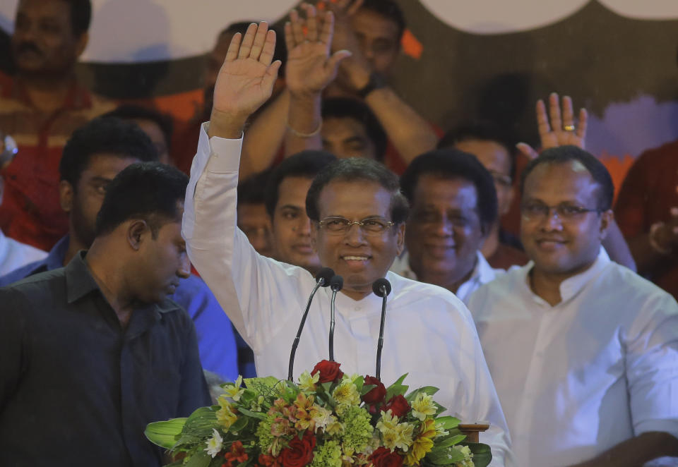 Sri Lankan president Maithripala Sirisena waves to supporters during a rally held out side the parliamentary complex in Colombo, Sri Lanka, Monday, Nov. 5, 2018. Thousands of Sri Lankans marched Monday in support of a new government led by the country's former strongman, highlighting the political polarization in the Indian Ocean island nation. The rally near Parliament comes amid a constitutional crisis sparked by President Maithripala Sirisena's move to oust Prime Minister Ranil Wickremesinghe, replace him with ex-leader Mahinda Rajapaksa, and suspend Parliament. (AP Photo/Eranga Jayawardena)