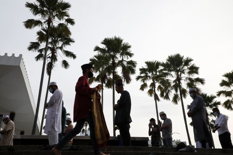 Muslims wearing protective masks prepare to pray outside the closed National Mosque while celebrating Eid al-Fitr, the Muslim festival marking the end the holy fasting month of Ramadan, amid the coronavirus disease (COVID-19) outbreak in Kuala Lumpur