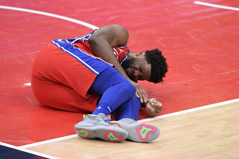 Philadelphia 76ers center Joel Embiid grimaces after an injury during the second half of the team's NBA basketball game against the Washington Wizards, Friday, March 12, 2021, in Washington. (AP Photo/Nick Wass)