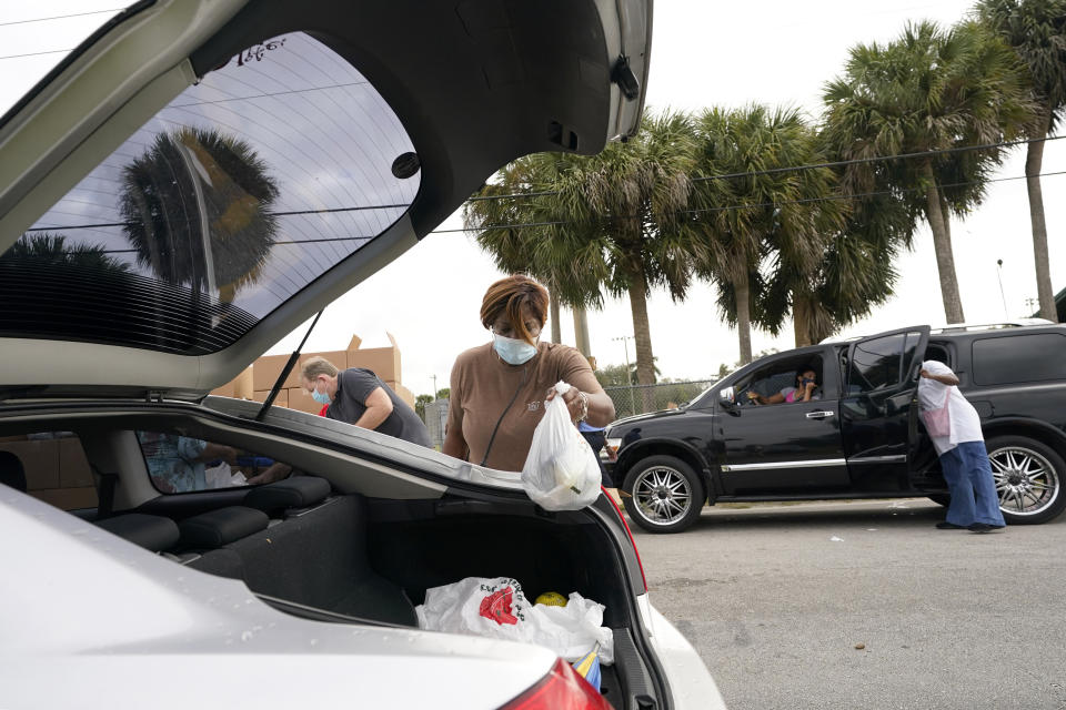 Renee Bracey loads a bag of food into a vehicle as she works with other volunteers at a food distribution for local residents sponsored by Feeding South Florida, Thursday, Jan. 28, 2021, in Florida City, Fla. (AP Photo/Lynne Sladky)