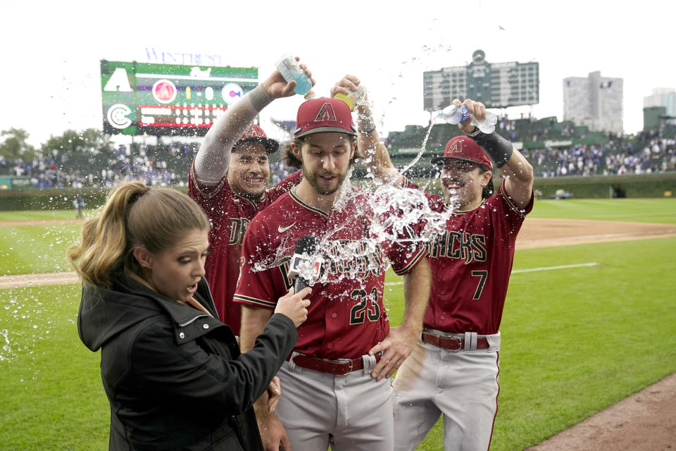 Alek Thomas, segundo a la izquierda, y Corbin Carroll (7) bañan al lanzador Zac Gallen (23), de los Diamondbacks de Arizona, mientras que la reportera de campo Sara Merrifield, izquierda, reacciona después de la victoria de Arizona sobre los Cachorros de Chicago, el viernes 8 de septiembre de 2023, en Chicago. (AP Foto/Charles Rex Arbogast)