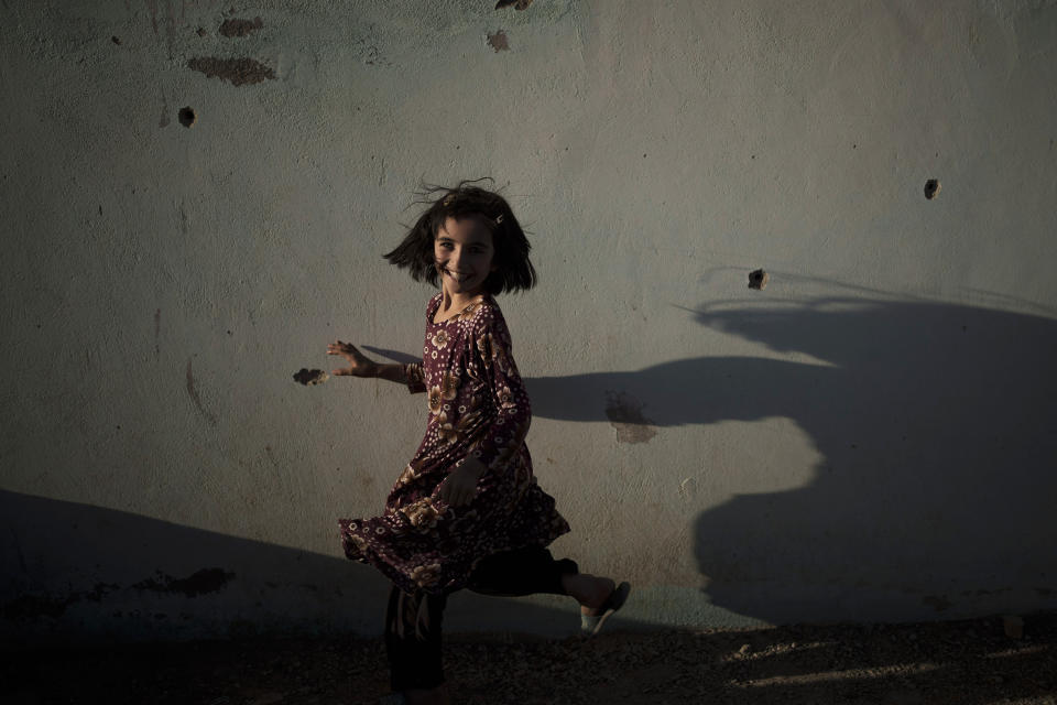 Zahra, 6, plays next to a wall marked by bullet holes at a village in Wardak province, Afghanistan, Monday, Oct. 11, 2021. (AP Photo/Felipe Dana)