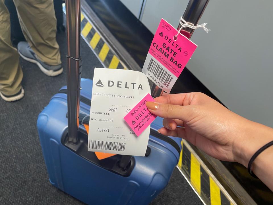 A hand holding a Delta valet check ticket next to a luggage.