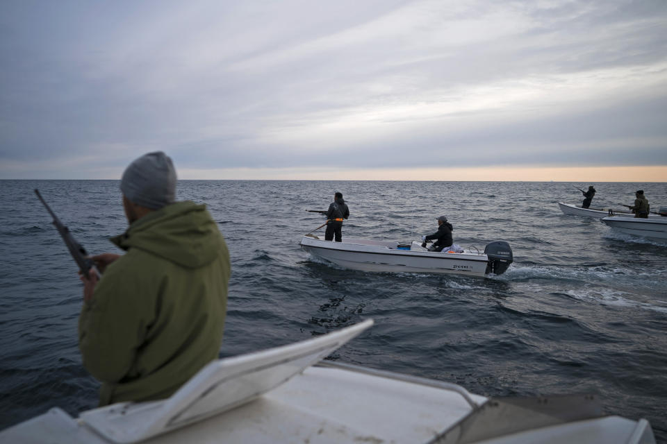 En esta fotografía del 16 de agosto de 2019, Mugu Utuaq (izquierda) recarga su fusil mientras navega junto con otros botes para cazar ballenas cerca de Kulusuk, Groenlandia. (AP Foto/Felipe Dana)