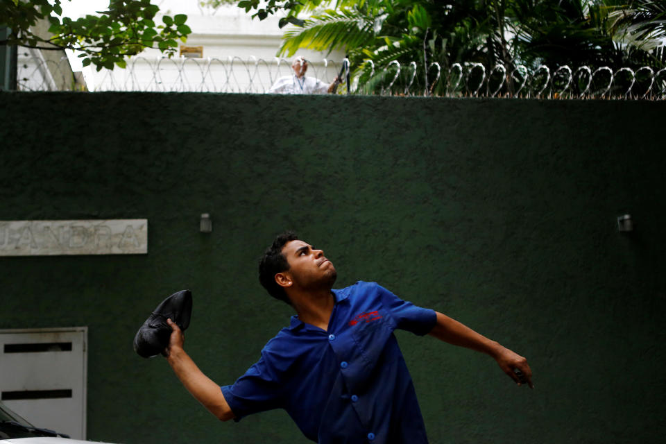 A worker prepares to throw a shoe at a mango tree to try to dislodge the fruits during his lunch break in Caracas on June 17, 2016.&nbsp;