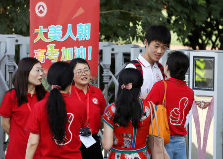 Teachers in red tee-shirts talk with a student before he enters the venue for the annual national college entrance examination, or "gaokao", in Beijing, China June 7, 2018. China Daily via REUTERS